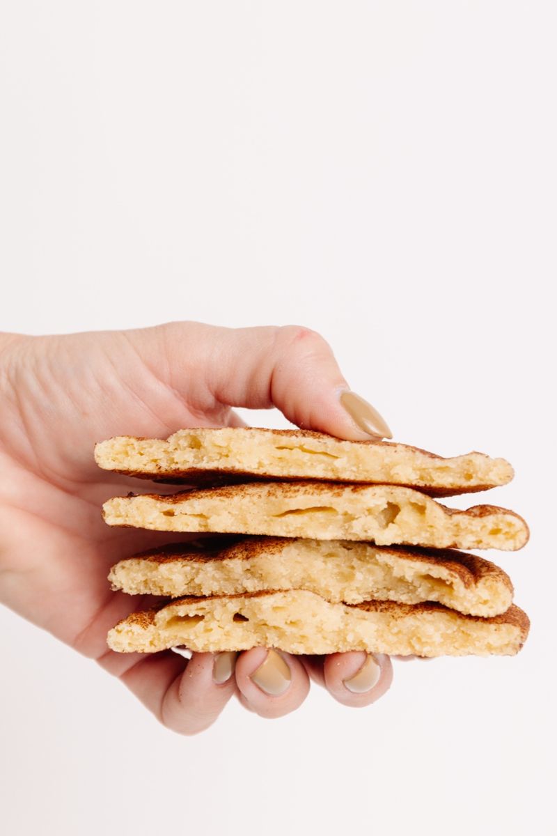 A fresh snickerdoodle cookie broken in half, revealing its soft, chewy interior.