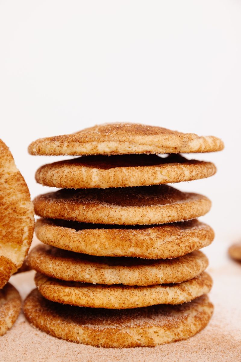 A stack of soft, golden-brown snickerdoodle cookies coated in cinnamon sugar.