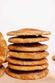 A stack of soft, golden-brown snickerdoodle cookies coated in cinnamon sugar.